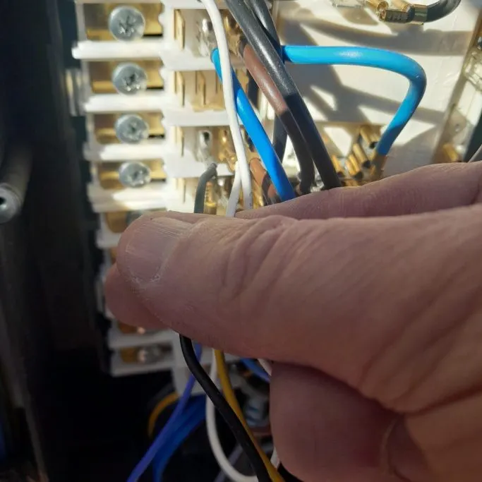 Noël Poulet, électricien à Marmande, raccordant un tableau électrique